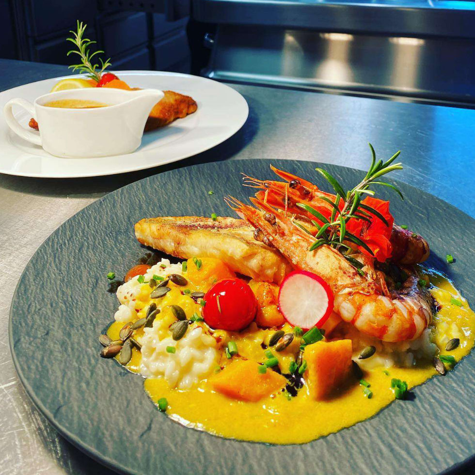 Fischgericht mit Garnelen und Gemüse angerichtet